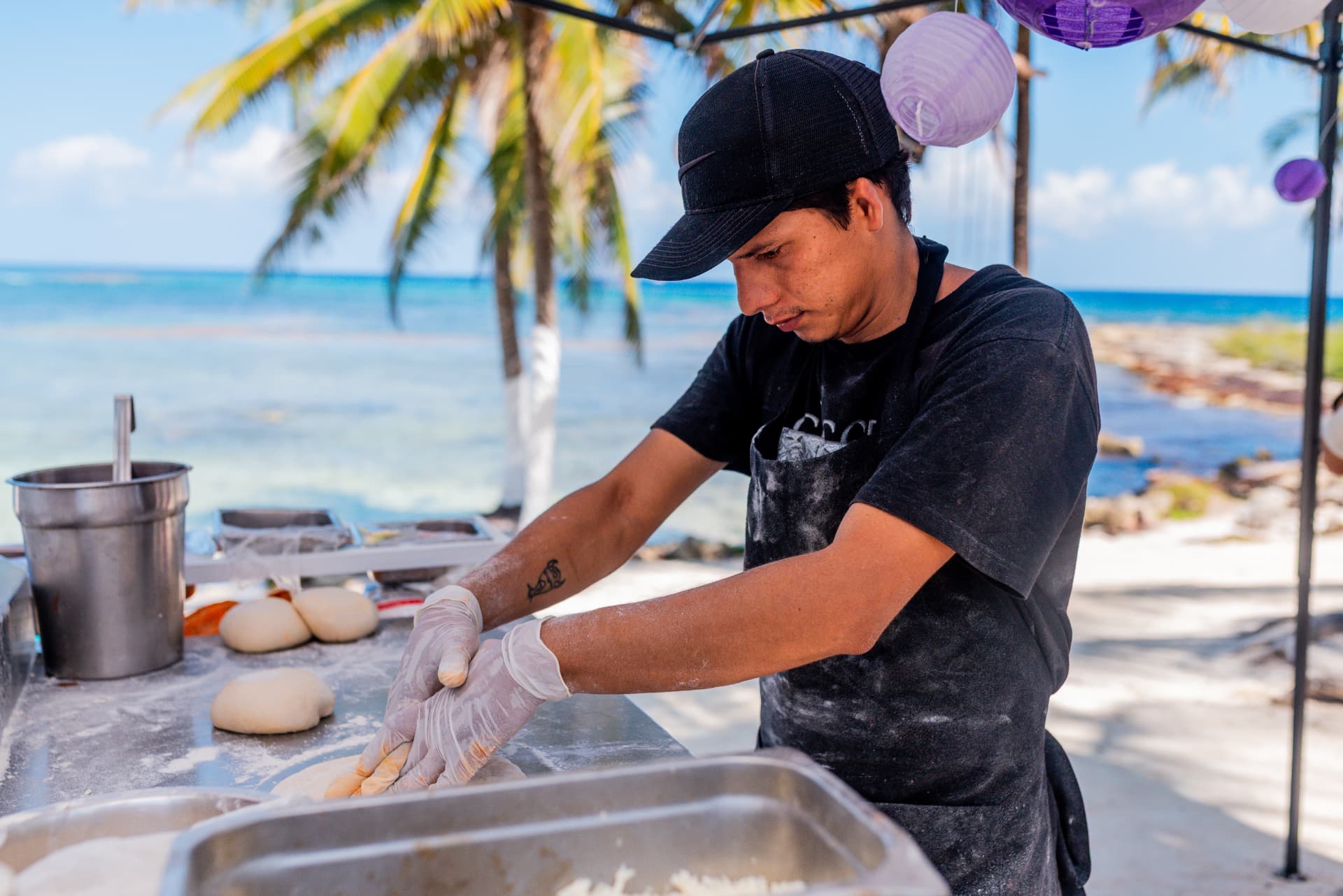 Dama Pizza Experience pizzaiolo shaping dough by hand at a beach event in the Riviera Maya